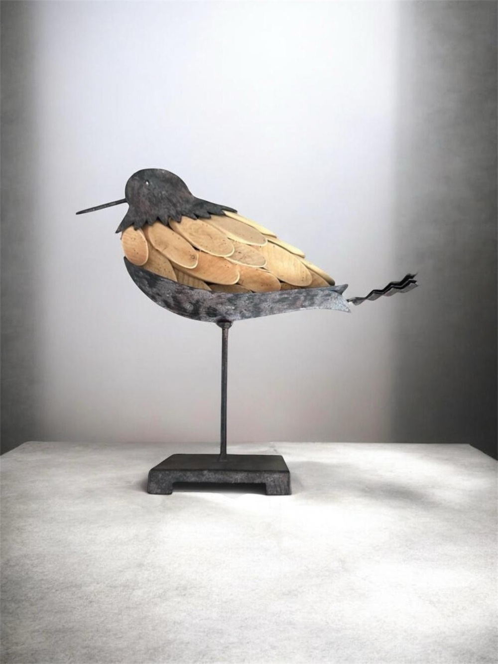 Handmade black metal art bird sculpture with layered natural wooden feathers